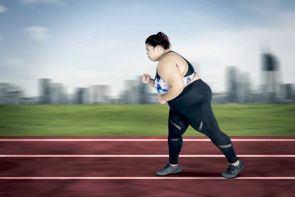 Obese woman sprinting exercises on the track