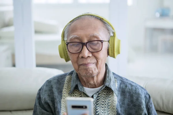 Senior man använder en tablett i biblioteket — Stockfoto