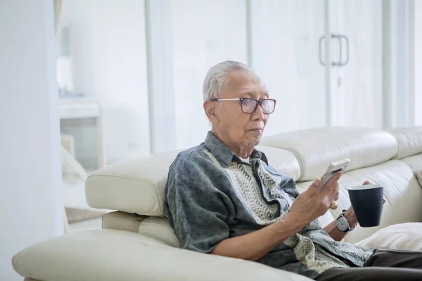 Starší muž používající tablet v knihovně — Stock fotografie