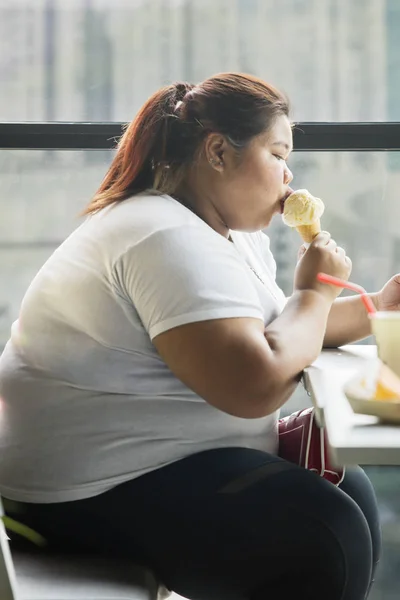 Overgewicht vrouw het eten van een ijsje in het café — Stockfoto