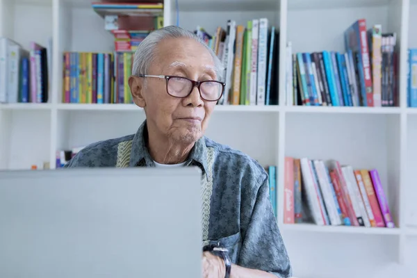Старший чоловік використовує планшет у бібліотеці — стокове фото