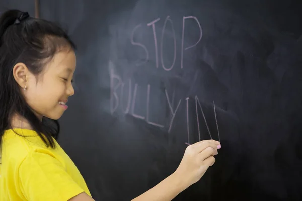 Triest klein meisje het schrijven van een tekst van stop pesten — Stockfoto