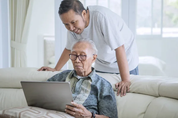 Homem sênior usando um tablet na biblioteca — Fotografia de Stock