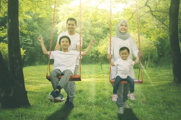 ブランコで遊ぶ若いイスラム教徒の家族 — ストック写真