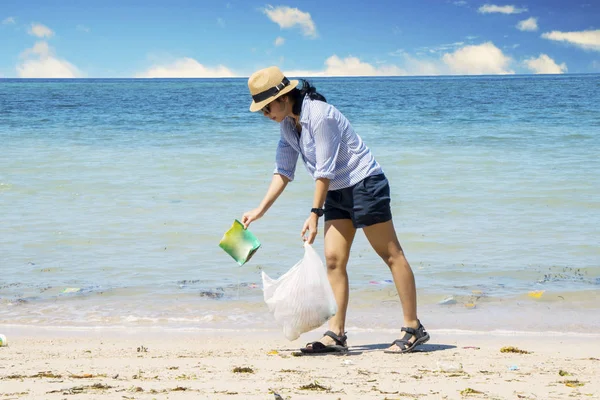 Młoda kobieta zbieranie odpadów z tworzyw sztucznych na plaży — Zdjęcie stockowe