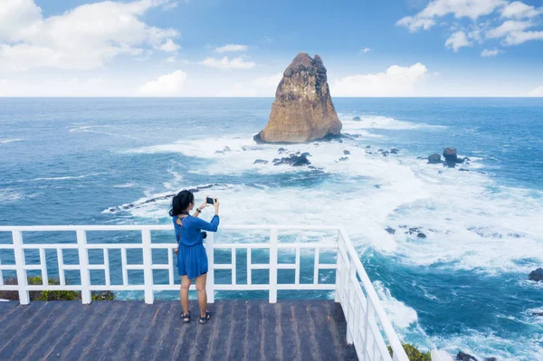 Mujer joven tomando una foto de hermoso paisaje marino —  Fotos de Stock