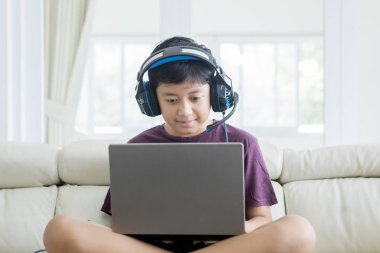 Bir dizüstü bilgisayar ve kulaklık kullanarak Asya preteen çocuk