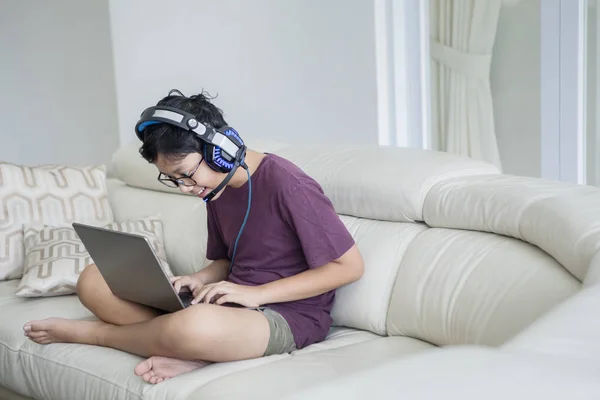 Asiatico teen ragazzo utilizzando un computer portatile su il divano — Foto Stock
