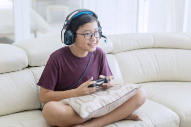 Mutlu genç çocuk bir joystick ile video oyunları oynuyor