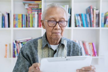 Kütüphanede dijital tablet kullanan yaşlı adam