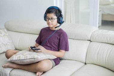 Genç çocuk kulaklıkla video oyunları oynuyor
