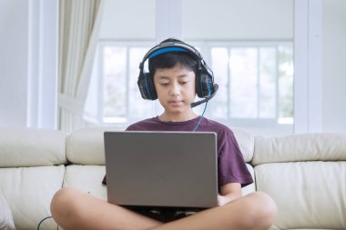 Genç çocuk kulaklıkla video oyunları oynuyor