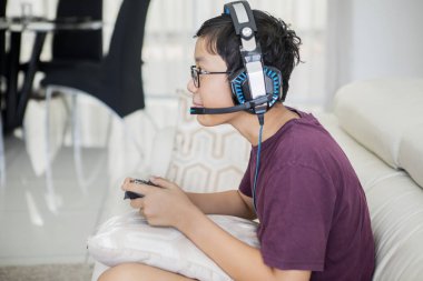 Genç çocuk bir joystick ile video oyunları oynuyor