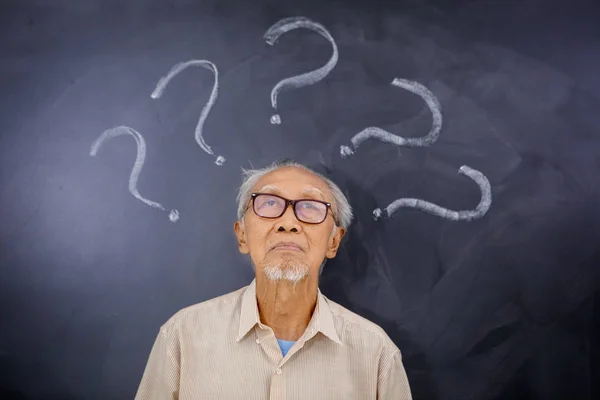 Elderly man looking at question marks