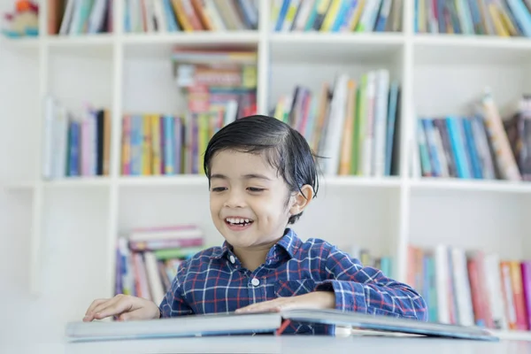 Asiático menino lendo um livro na biblioteca — Fotografia de Stock