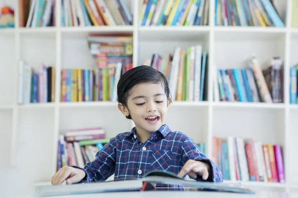 Милый мальчик, читающий книгу в библиотеке. — стоковое фото