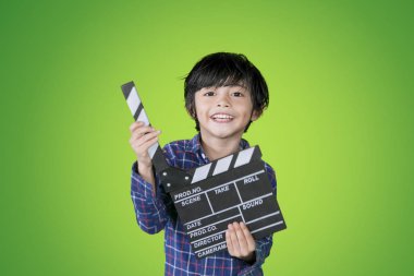 Mutlu küçük çocuk stüdyoda bir clapperboard tutan