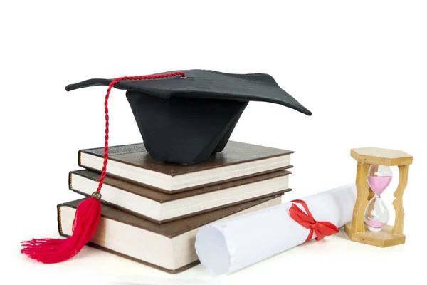Graduation cap on a pile of books with hourglass — Stock Photo, Image