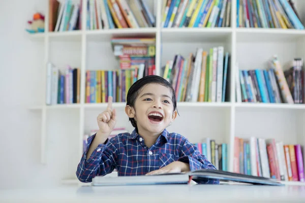 Rapazinho feliz ter uma ideia na biblioteca — Fotografia de Stock