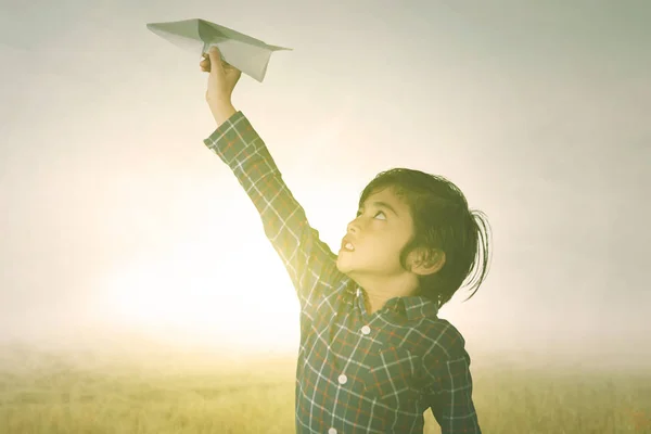 Мальчик играет на бумажном самолёте в парке — стоковое фото