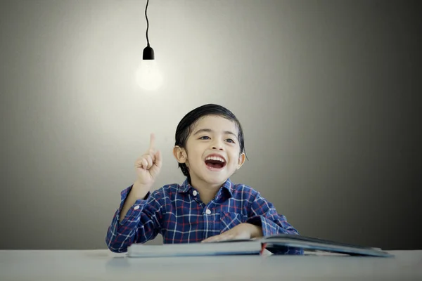 Malý chlapec, který ukazoval na žárovku, má nápad — Stock fotografie