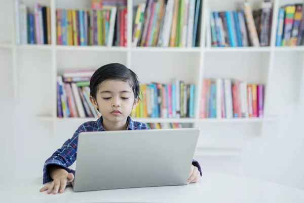 Kleiner Junge lernt mit Laptop in der Bibliothek — Stockfoto