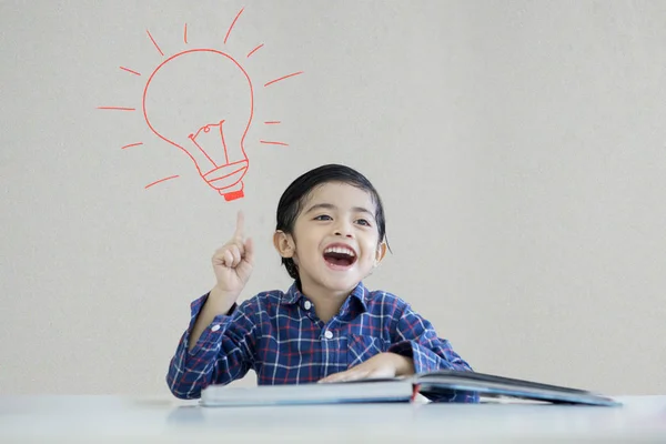 Liten pojke tänkande en idé under en glödlampa — Stockfoto