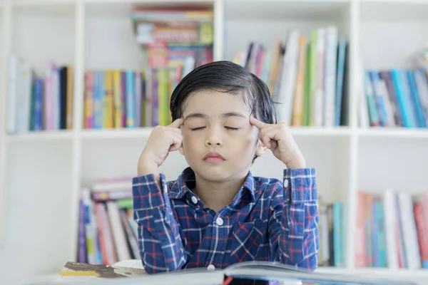 Chlapeček uvažuje s očima uzavřenými v knihovně — Stock fotografie