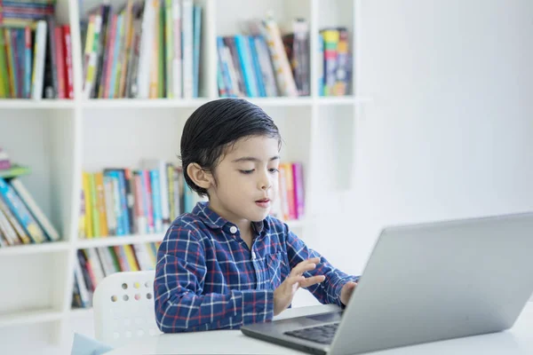 Malý chlapec používající přenosný počítač v knihovně — Stock fotografie