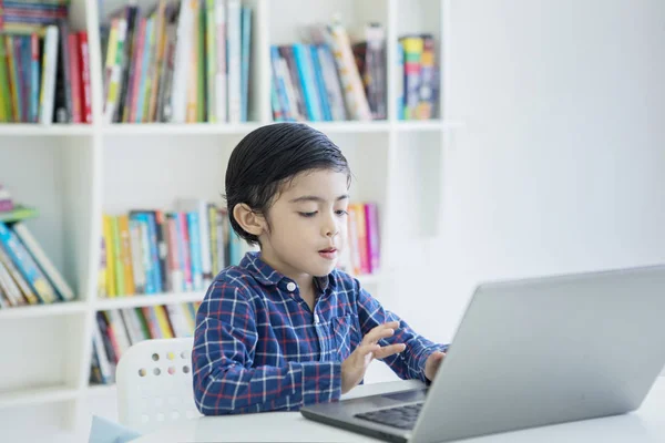 Ragazzino che usa un portatile in biblioteca — Foto Stock