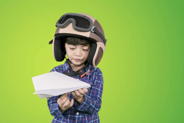 Menino usa um capacete e segura o avião de papel — Fotografia de Stock