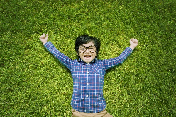 잔디에 누워 웃고 있는 어린 소년 — 스톡 사진