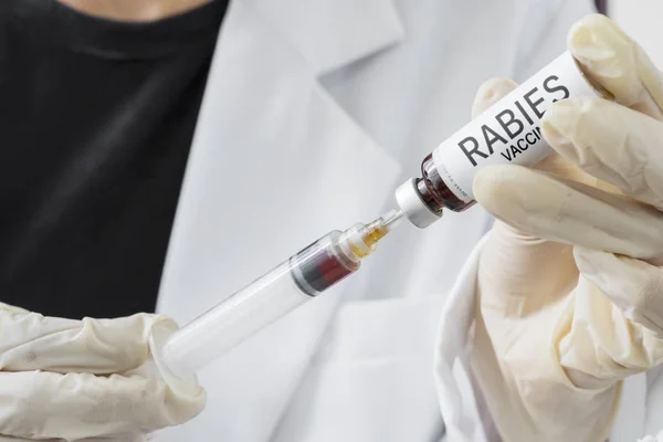 Manos del médico llenando una jeringa con la vacuna contra la rabia — Foto de Stock