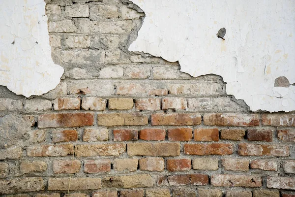 Oude bakstenen muur met beschadigde witte pleister — Stockfoto