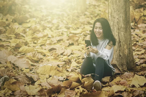 Mulher feliz usando telefone celular no parque de outono — Fotografia de Stock