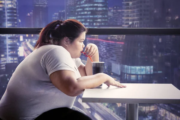 Mujer con sobrepeso bebiendo cola en la cafetería por la noche — Foto de Stock