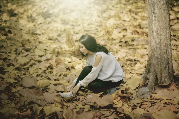 핸드폰을 들고 가을 공원에 앉아 있는 여성 — 스톡 사진