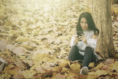 Sonbahar parkında cep telefonu kullanan kadın