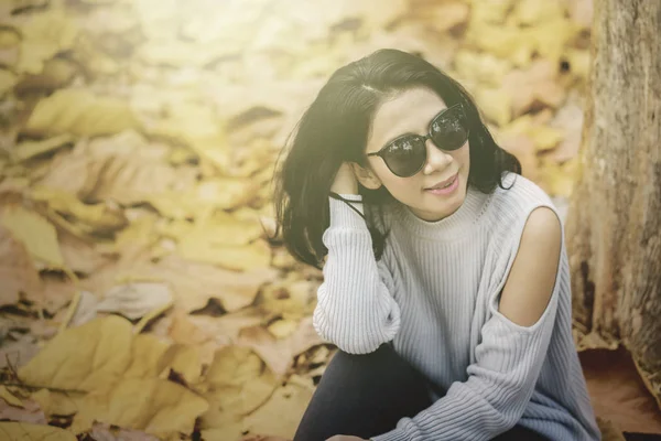 Frau mit Sonnenbrille sitzt im Herbstpark — Stockfoto