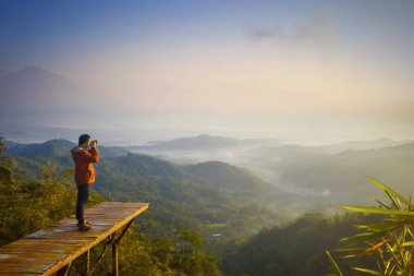 Ahşap köprüde oturan genç adam