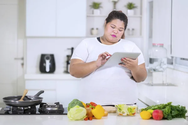 Mulher gorda olhando receitas em um tablet — Fotografia de Stock