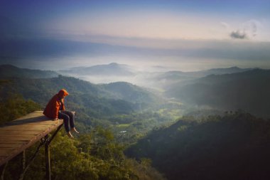 Ahşap köprüde oturan genç adam