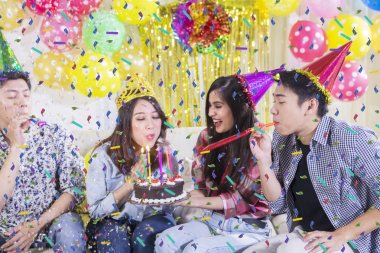 Arkadaşlarıyla mum üfleyen genç kadın