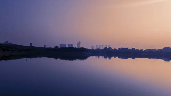 Rascacielos y árboles con embalse al atardecer —  Fotos de Stock