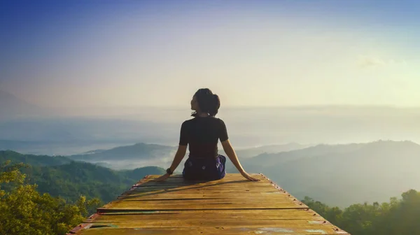 Młoda kobieta siedzi i cieszy widok na wzgórze Ngisis — Zdjęcie stockowe