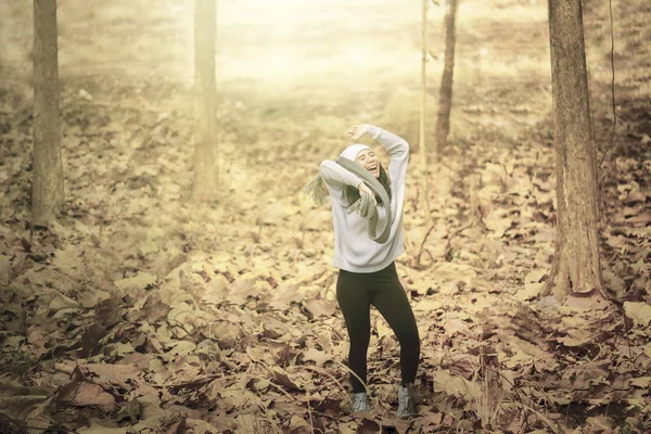 Fröhliche Frau wirft getrocknetes Herbstlaub in Park — Stockfoto