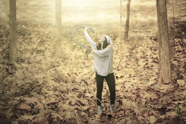Радісна жінка кидає сухе осіннє листя в парку — стокове фото