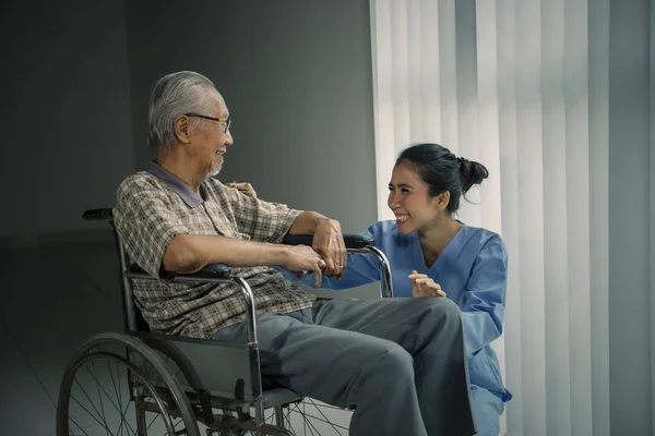 Viejo riendo con su enfermera cerca de la ventana —  Fotos de Stock