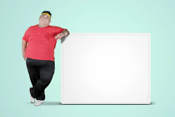 Overweight man leaning on a blank whiteboard — Stock Photo, Image