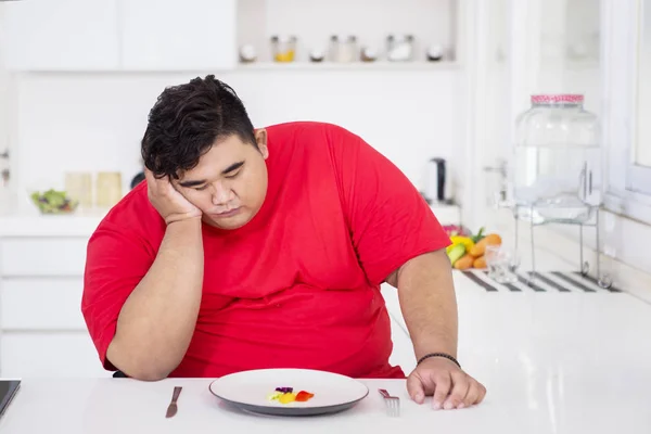 Överviktiga mannen ser olycklig att äta sallad — Stockfoto